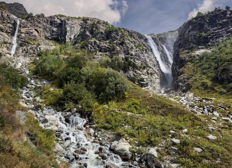 A mountainous landscape with multiple waterfalls and a rocky riverbed. 2