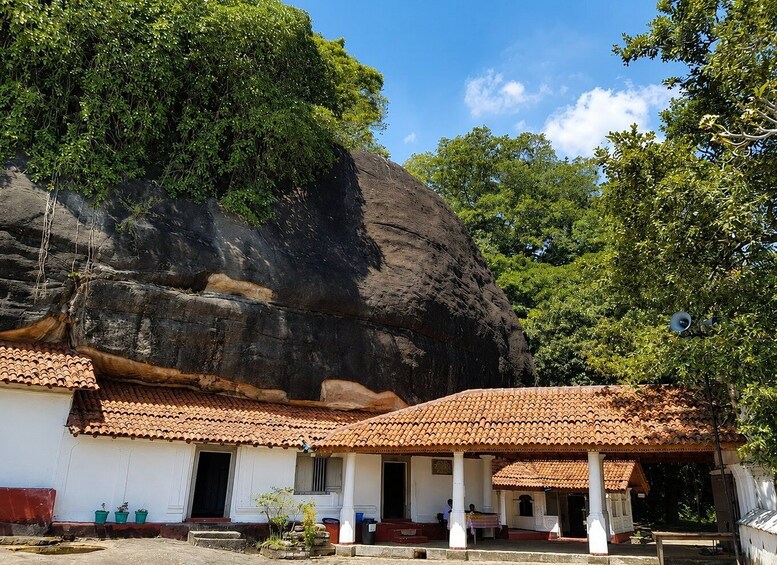 A traditional building with a tiled roof, white walls, and a large rock formation in the background. 2
