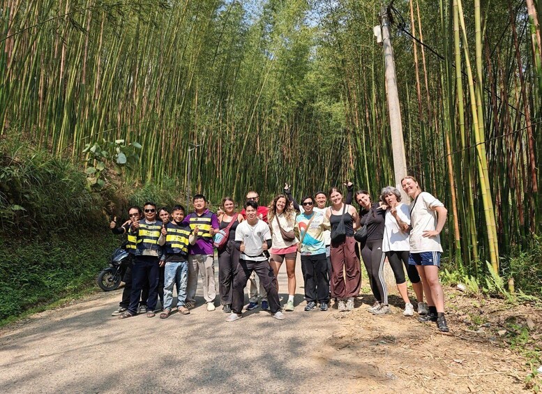 A group of people standing on a dirt road surrounded by bamboo forest. 2