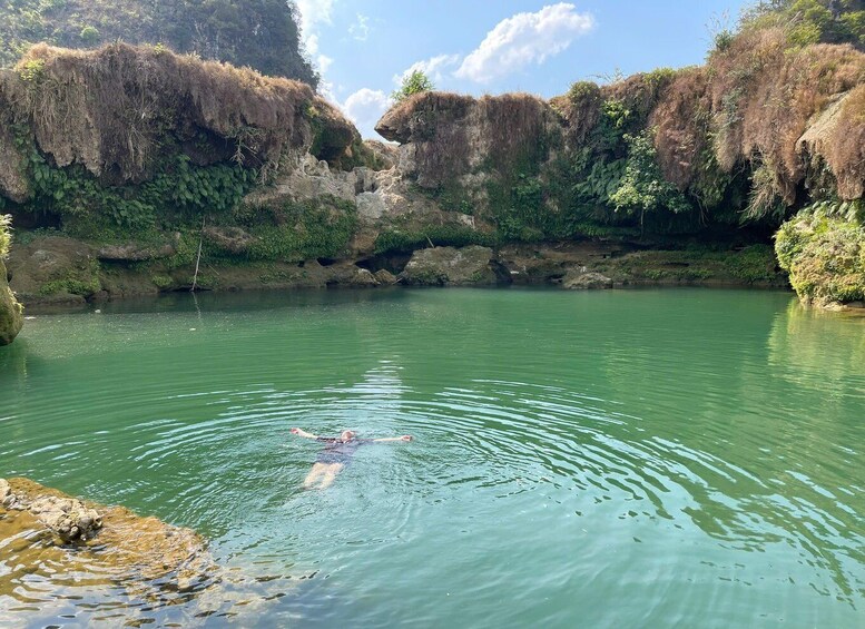 A swimmer in a natural pool surrounded by rocky cliffs. 3