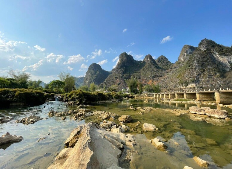 A river with clear water, rocky terrain, and a bridge in a mountainous area. 5