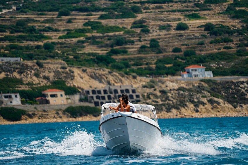 A boat speeding across a body of water with a hilly coastline in the background. 5