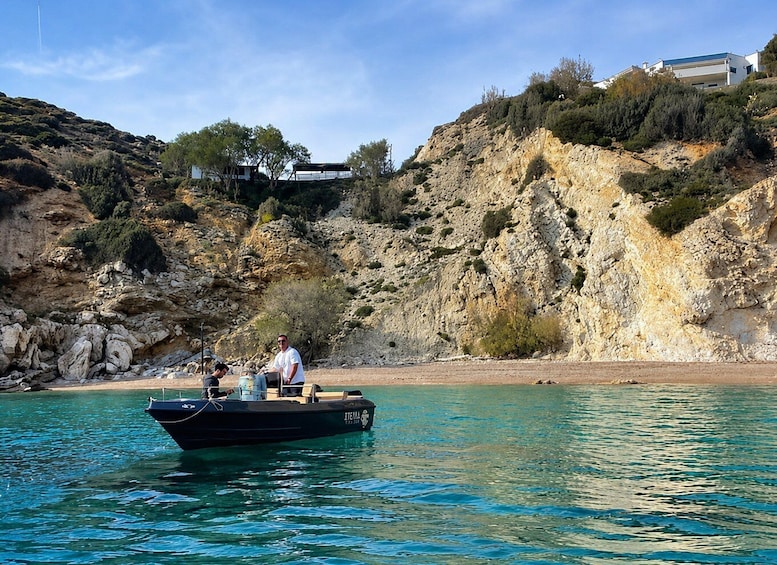 A boat on calm waters with rocky cliffs and buildings in the background. 1