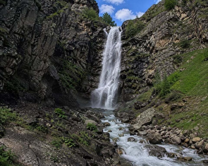A waterfall cascading down a rocky gorge surrounded by greenery. 3