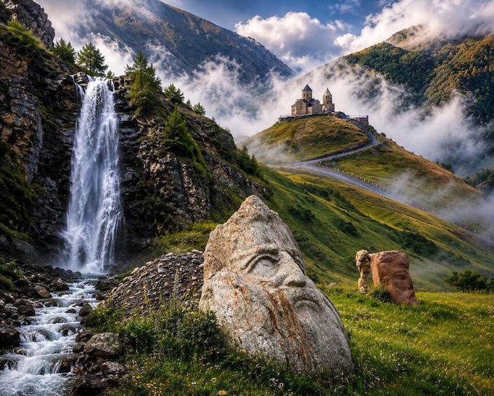 A waterfall, a stone face, and a church on a hill. 1