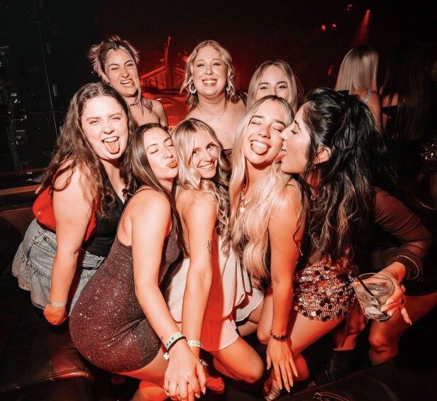 A group of people in a dimly lit indoor setting, possibly a club or party venue. 1