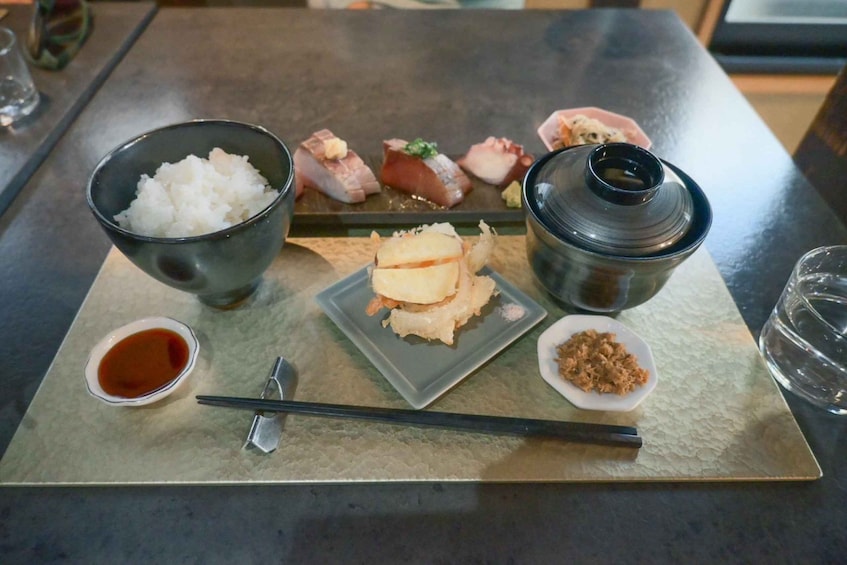 A traditional Japanese meal with rice, sashimi, and a bowl of soy sauce. 2