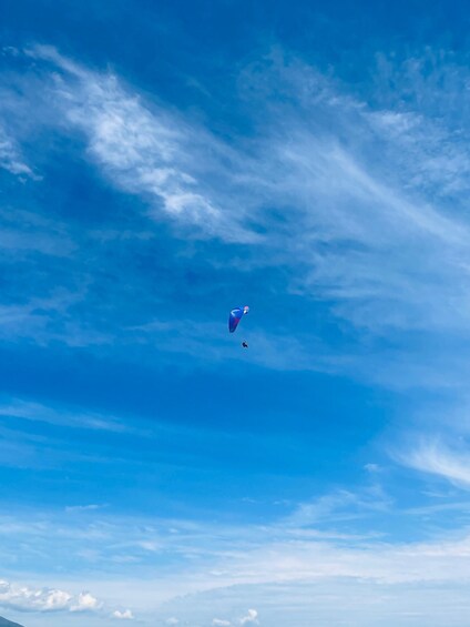 A clear blue sky with scattered clouds and a parachute descending. 4