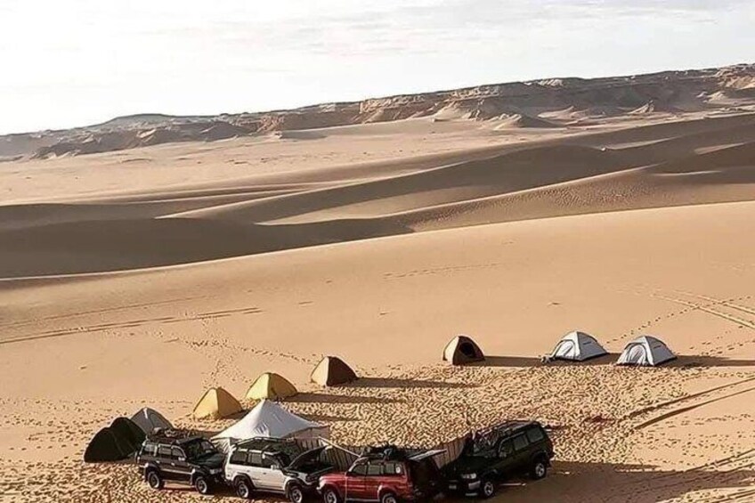 A desert campsite with tents and vehicles. 5