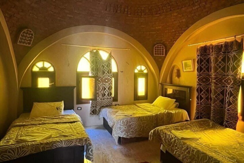 A room with three beds, arched ceilings, and patterned curtains. 4