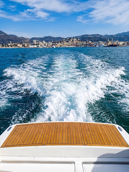 A boat's wake in a body of water with a cityscape in the background. 3