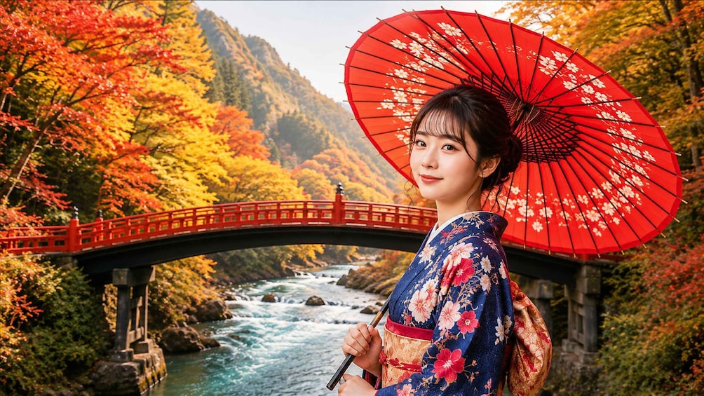 A person in traditional attire holding a red parasol, standing by a river with a bridge and autumn foliage. 5