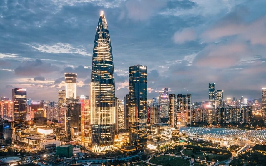 A cityscape at dusk with illuminated skyscrapers and a prominent curved building. 4
