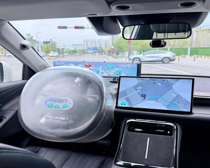 A car's interior with a steering wheel cover, a rearview camera, and a GPS navigation screen. 3