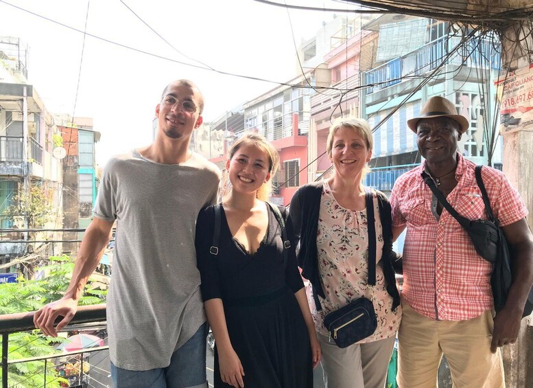 Four people standing on a balcony with buildings in the background. 4
