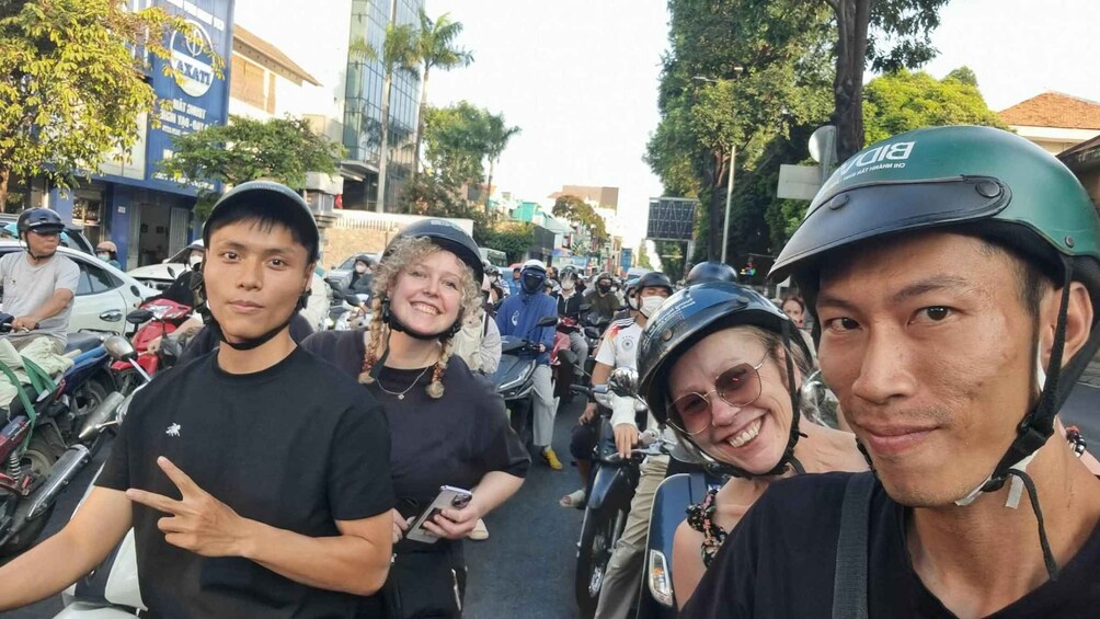 A group of people on motorcycles on a street with buildings and trees in the background. 2