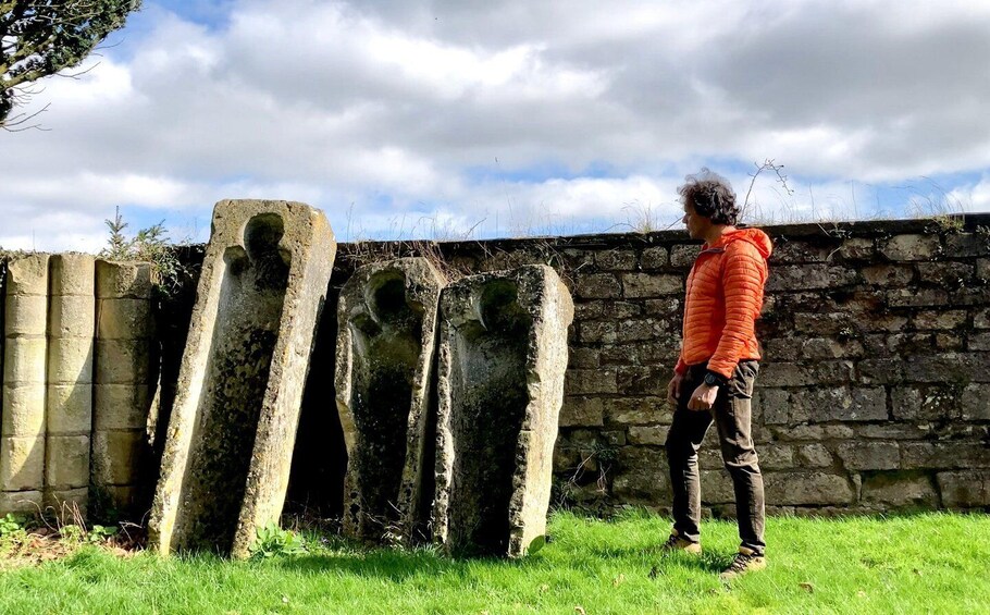 A person standing next to a stone wall with vertical stone structures. 1