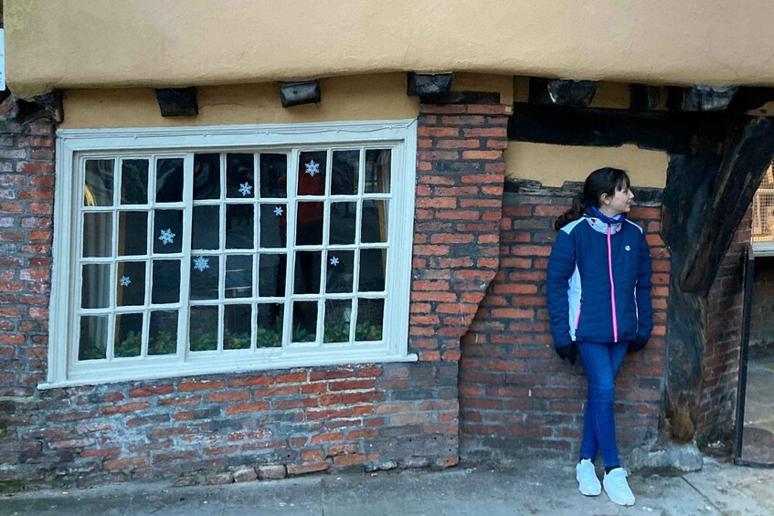 A person standing in front of a brick building with a white window and snowflake decorations. 5