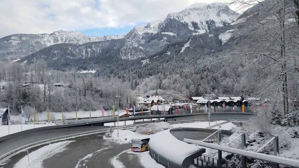 A snow-covered mountain landscape with a winding road, a bus, and various flags. 3