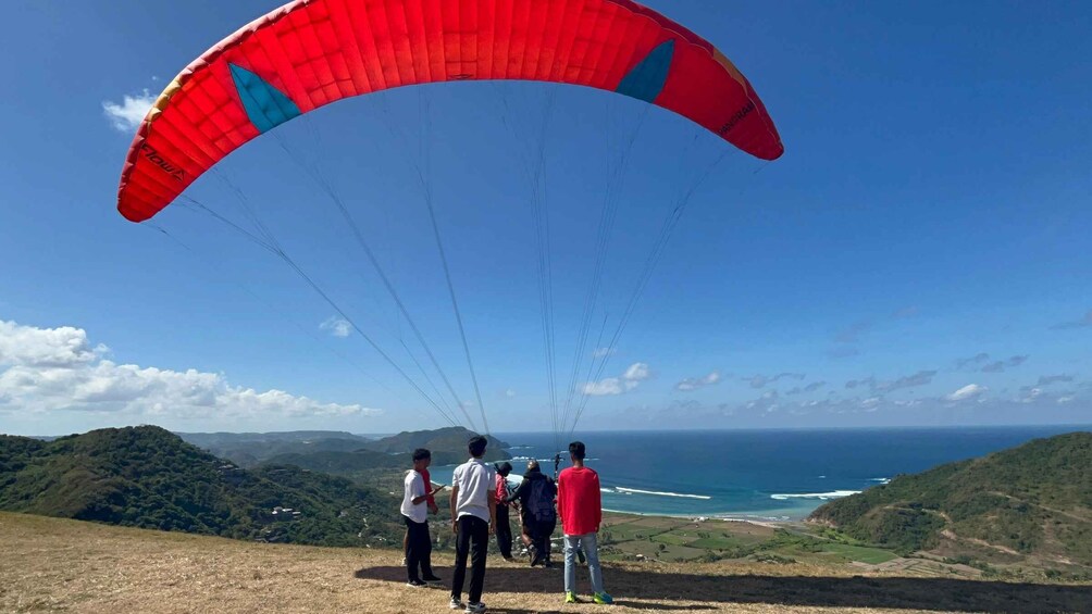 A group of people paragliding over a coastal landscape. 5