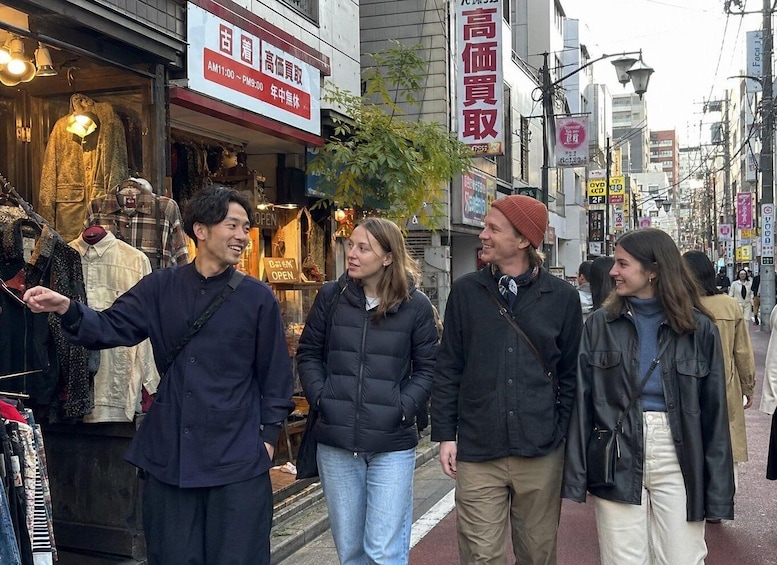 A group of people walking on a city street with shops and signs in the background. 5
