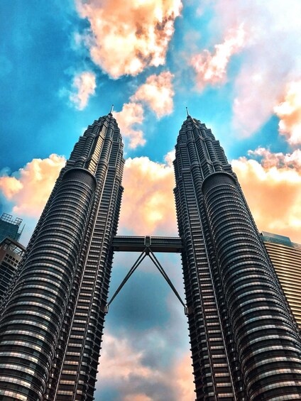 The Petronas Twin Towers with a bridge connecting them, under a partly cloudy sky. 2