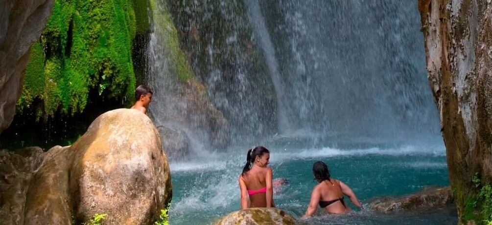 A waterfall, rocky terrain, and people in a natural setting. 1