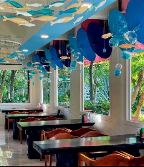 A restaurant interior with tables, chairs, and decorative fish hanging from the ceiling. 3