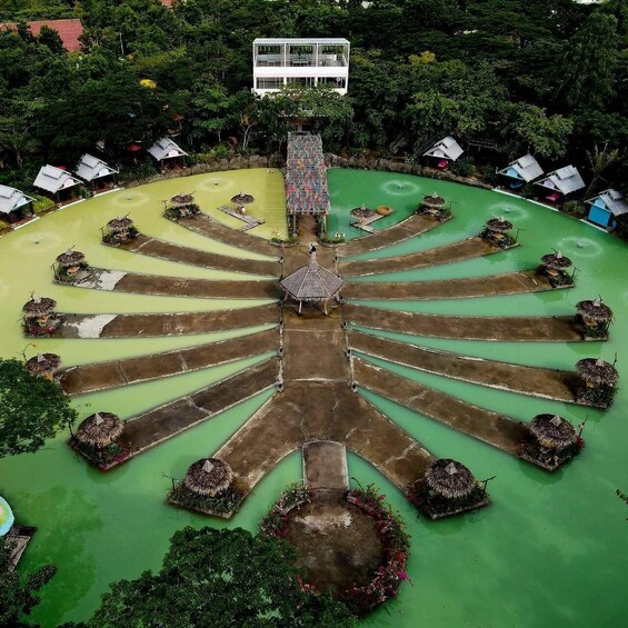 A symmetrical garden with a central pavilion, surrounded by a circular water feature and thatched-roof structures. 1