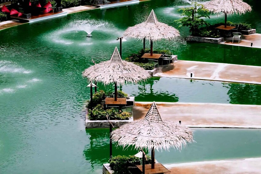A pool with thatched umbrellas and a fountain. 5