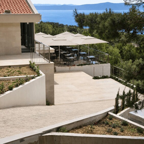 A modern outdoor dining area with tables and umbrellas, overlooking a coastal landscape. 4