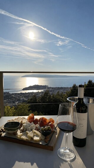 A table with cheese, olives, almonds, a bottle of wine, and a glass, overlooking a coastal city with a clear sky and a bridge. 5