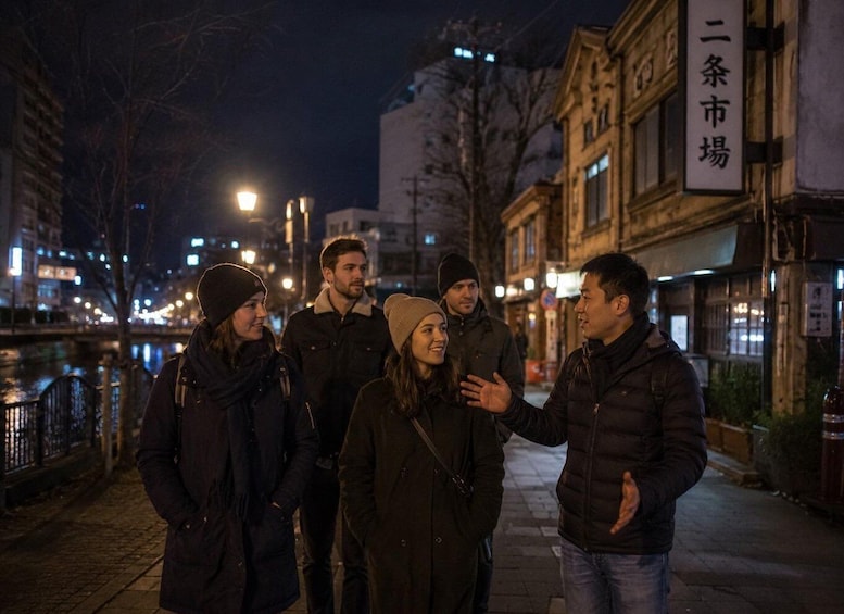 A group of people standing on a city street at night. 3
