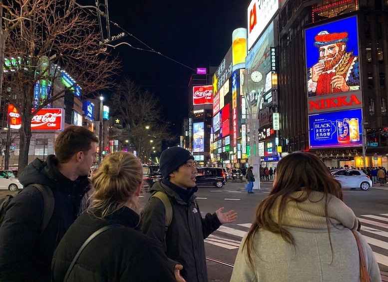 A nighttime urban street scene with illuminated billboards and a crosswalk. 1