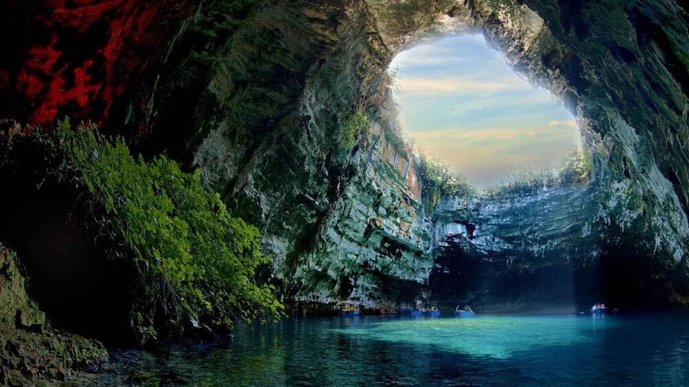 A cave with a natural archway, water, and greenery. 4