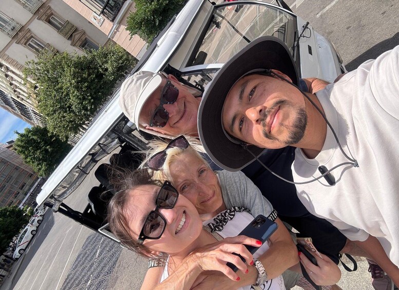 Three people taking a selfie with a white vehicle in an urban setting. 4