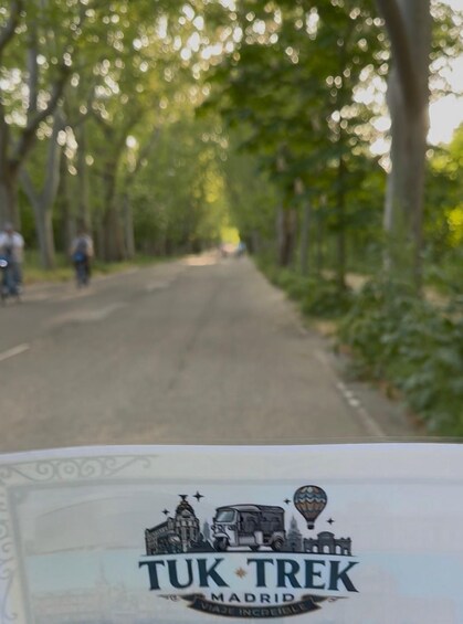 A road lined with trees and a Tuk-Tuk sign. 1