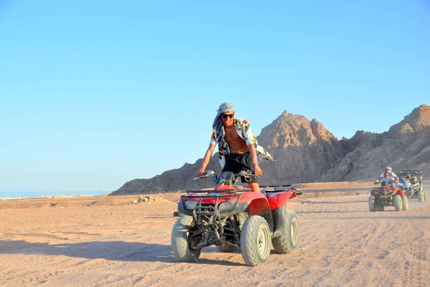 A person riding an ATV in a desert with mountains in the background. 2
