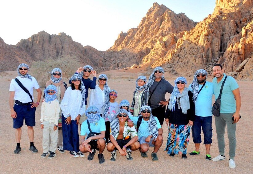 A group of people in a desert landscape with rocky mountains in the background. 4
