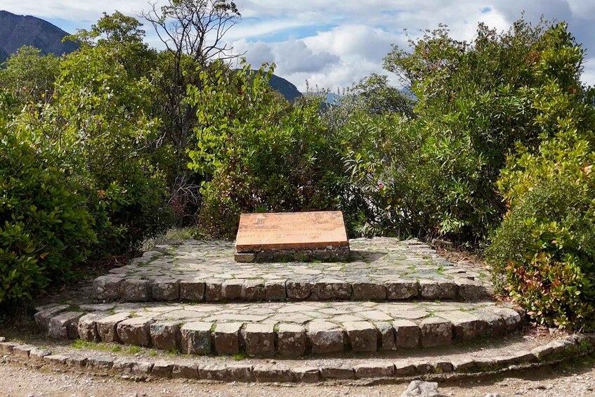 A stone bench surrounded by lush greenery and a mountainous backdrop. 2
