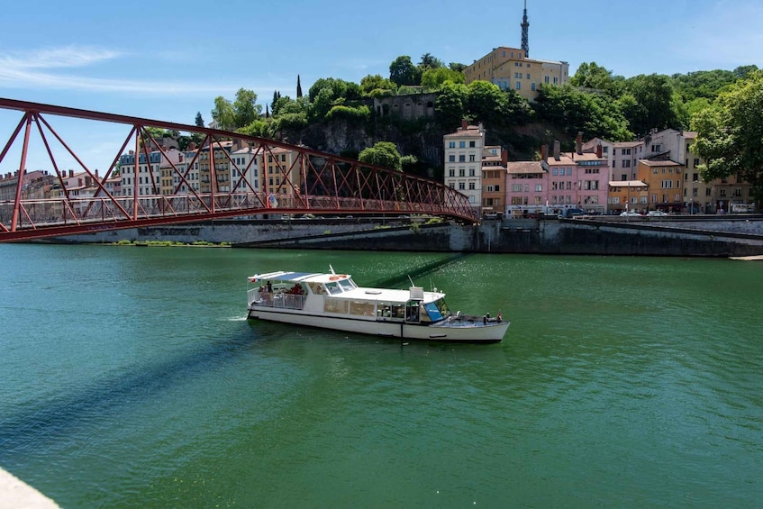 A boat on a river with a red bridge and buildings in the background. 5