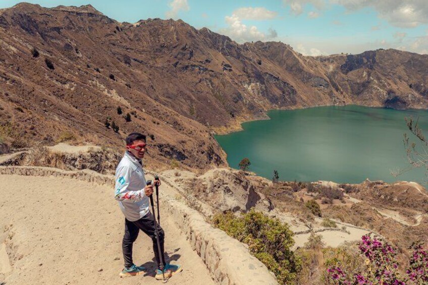 A person hiking on a dirt path with a mountain and a lake in the background. 3
