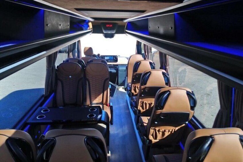 The interior of a bus with brown leather seats and a digital display. 2