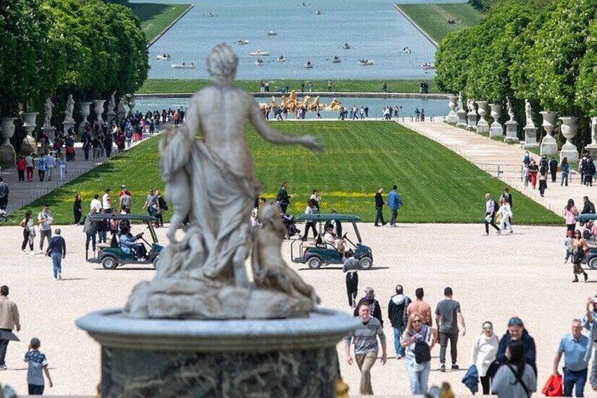 A statue in the foreground, a large open plaza, and a body of water with boats in the background. 2