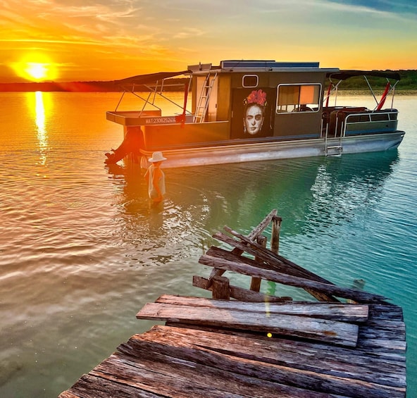 A boat docked at a wooden pier during sunset. 2