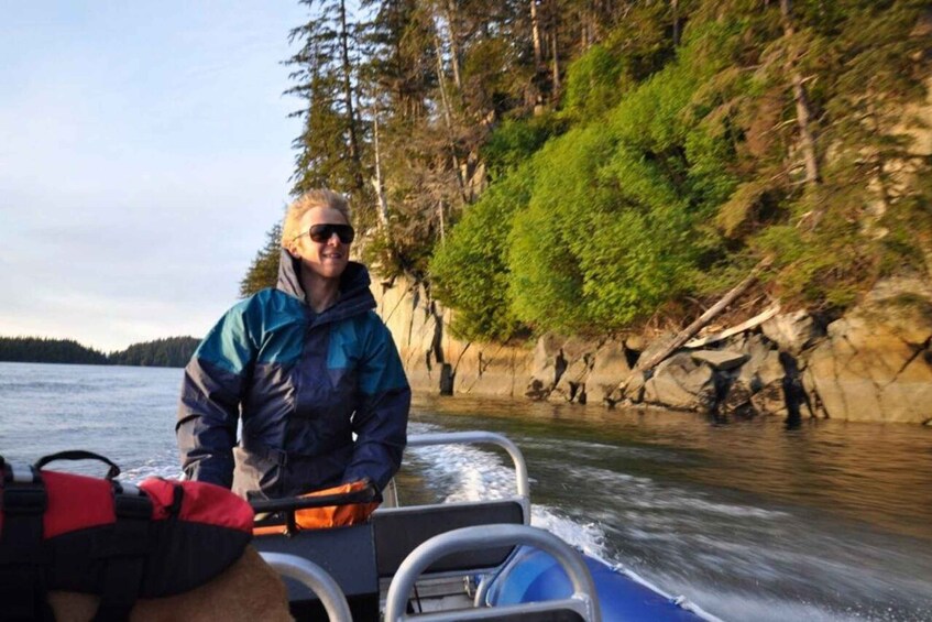 A person on a boat near a rocky shoreline with trees. 2