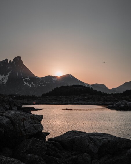 A sunset over a lake with mountains in the background. 1