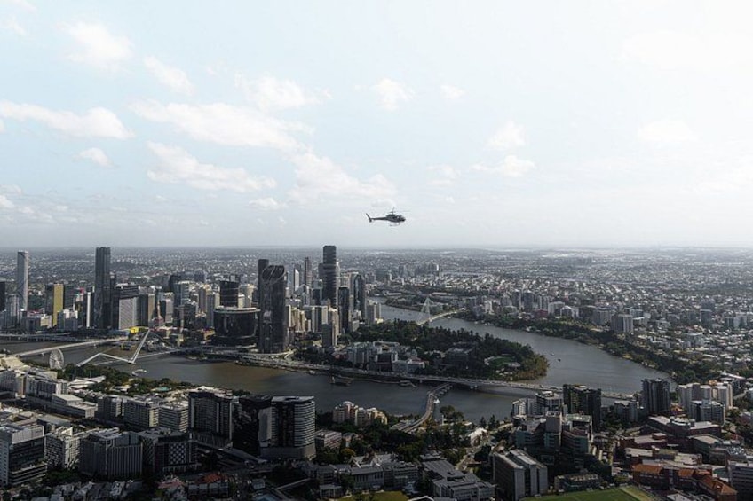A helicopter flying over a city with a river and bridges. 1