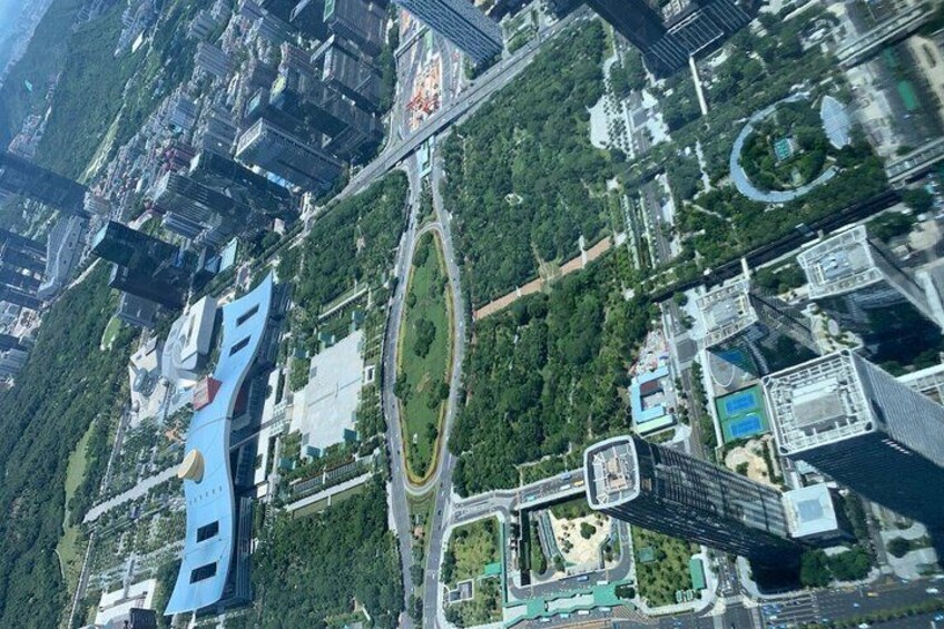 A cityscape with modern high-rise buildings, a large blue structure, and a central park area. 3