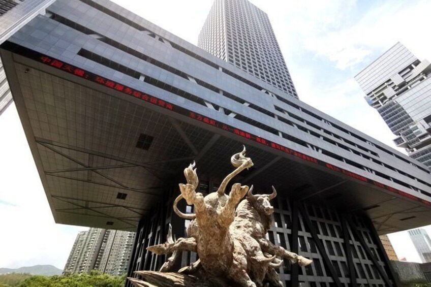 A modern building with a large sculpture of a bull in front. 2